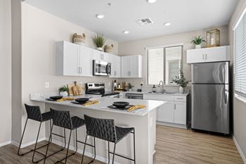 An open kitchen with white cabinets and a large island with three stools